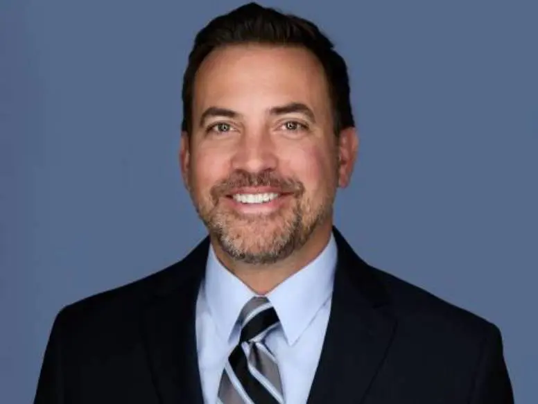Smiling man in suit with blue background.